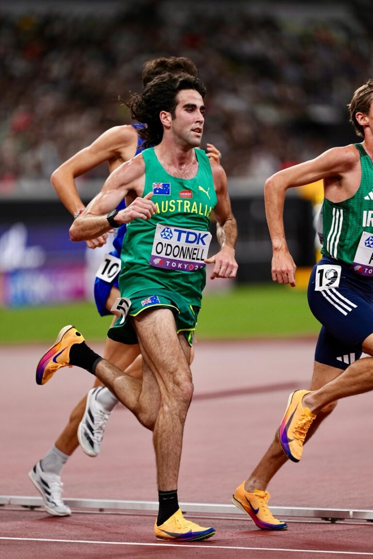 Australian sprinter in a green Australia kit runs on a track; bib reads O'DONNELL, Tokyo 2020 (Olympics).