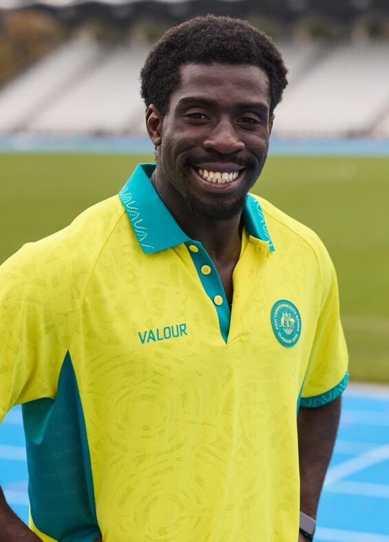Smiling man in a bright yellow and teal polo on a running track, posing for a photo.