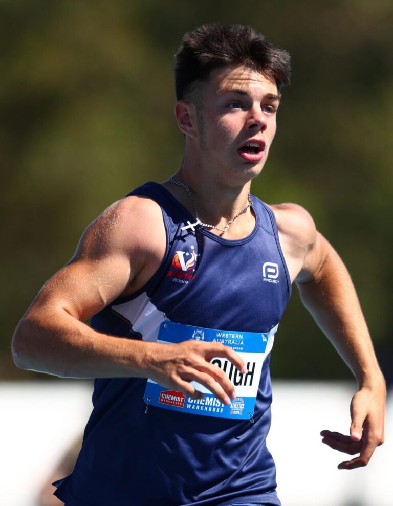 Young male athlete in a blue singlet racing outdoors, mid-stride with race bib visible