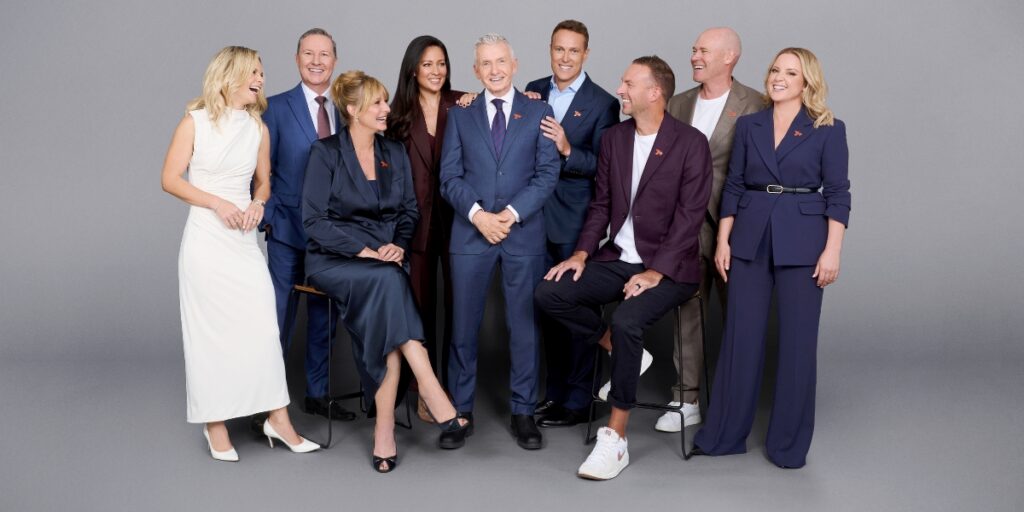 Group of ten business professionals in formal attire posing and smiling in a studio.