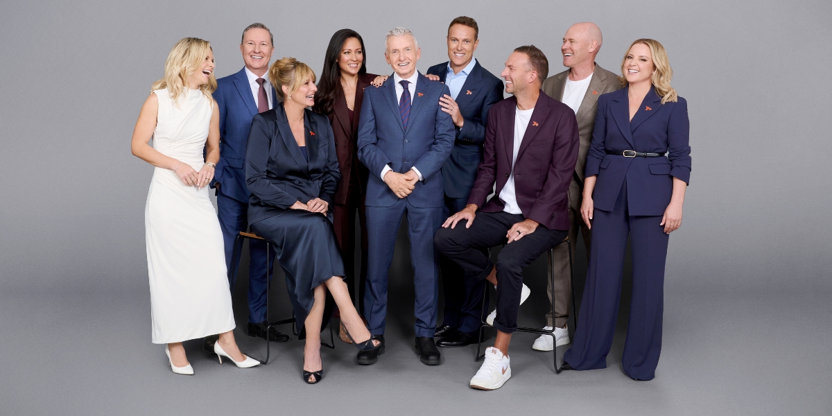 Group of ten business professionals in formal attire posing and smiling in a studio.