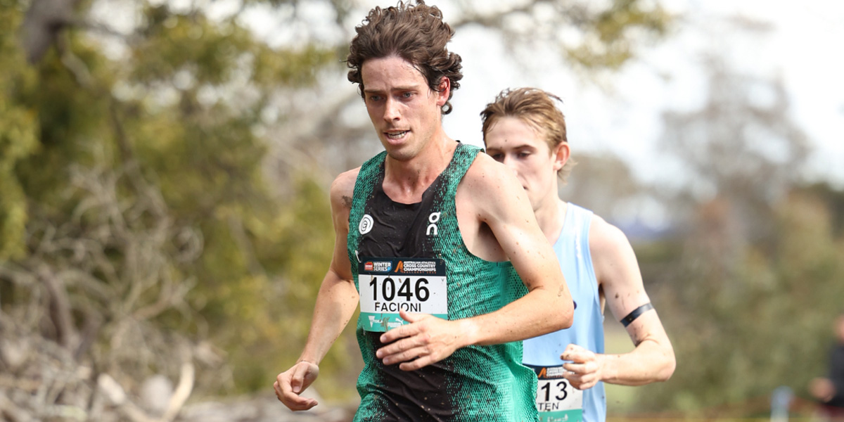 Two male runners race on a dirt trail; the front runner wears a green singlet with bib 1046 reading FACONI, the second runner in light blue follows behind.
