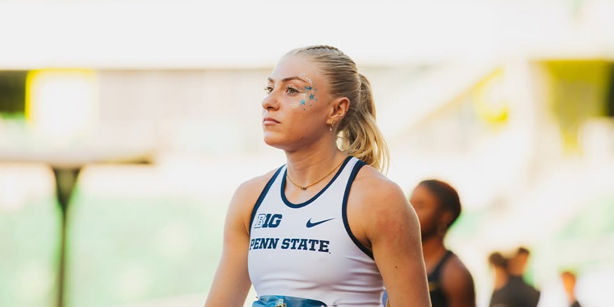 Female athlete in a Penn State white tank top, facing left with blue star glitter on her face, outdoors.